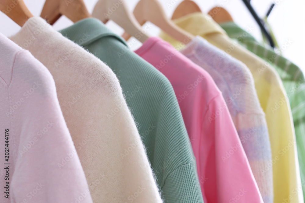 Fototapeta premium Different clothes hanging on rack against white background, closeup