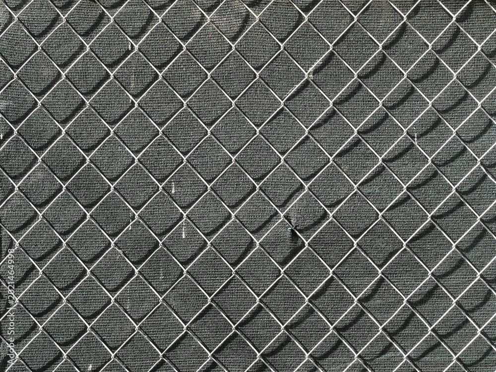 Fototapeta premium Chain link fence with diamond pattern against dark background. Front view with clear structure and geometry. Copy space.