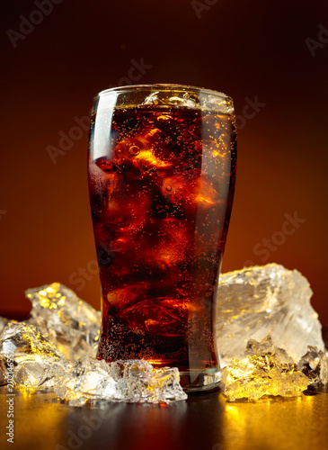 Fotografie Fizz sparkling cola bubbly soda pop with crushed ice on a black table