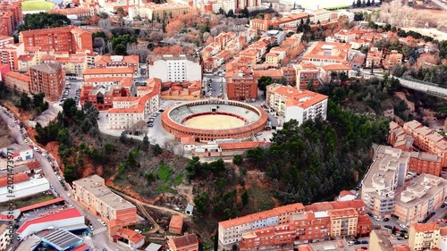 Classic circular bullring surrounded by trees and urban residential buildings. Aerial view of a circular bullring plaza de toros.