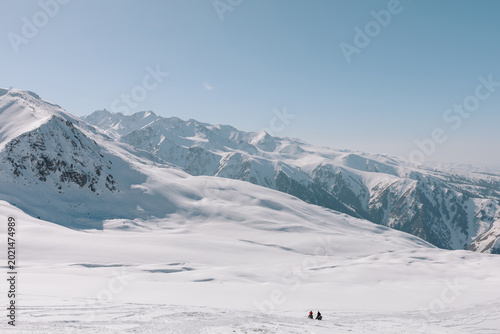 Wide winter landscape of snow-covered Tian Shan mountains at Karakol ski base near Karakol, Issyk-Kul Region, Kyrgyzstan, with two skiers in the valley