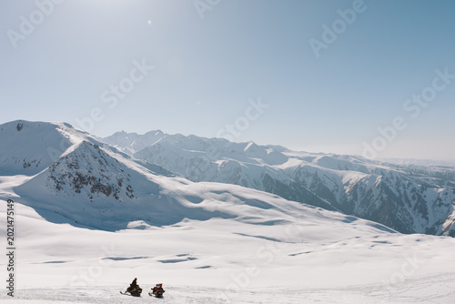 Картината върху платно Two snowmobiles cross a wide snowy plateau at Karakol ski base, Issyk-Kul Region