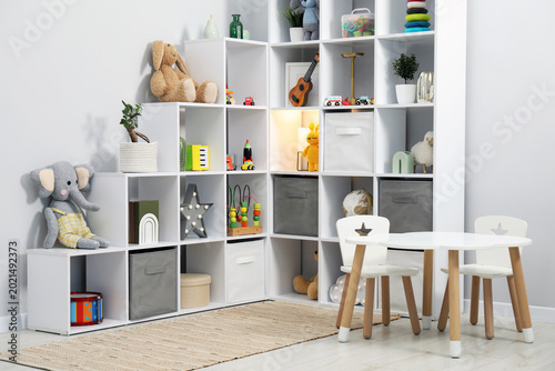 Foto Shelving unit with different toys and decor near light grey wall in child's room