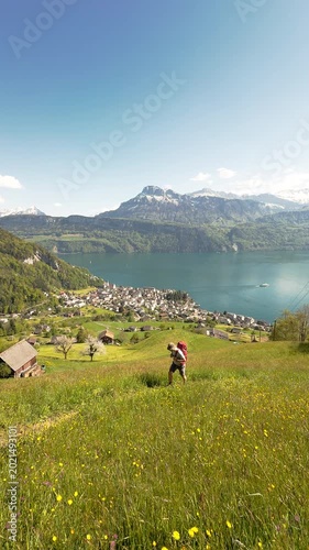 Hiker with Backpack on Spring Meadow Above Village Gersau and Lake Lucerne, Vitznauerstock Trail, Rigi, Switzerland