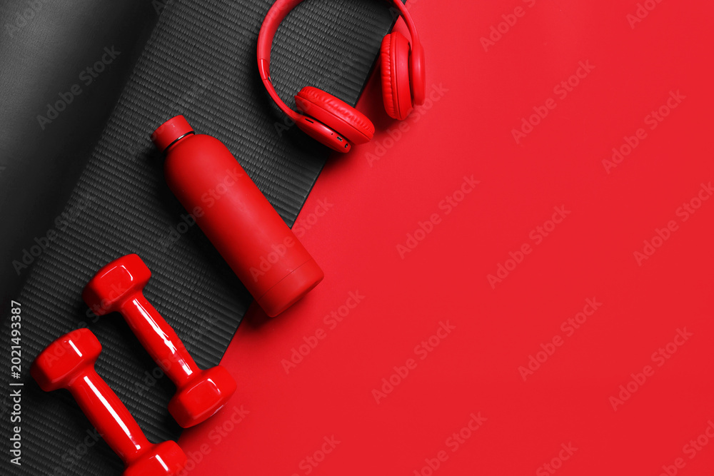 Fototapeta premium Sports equipment, water bottle and headphones on red background, flat lay. Space for text
