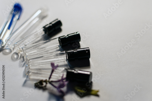 Bild auf Leinwand A row of glass perfume sample atomizers with black spray heads on a white surfac