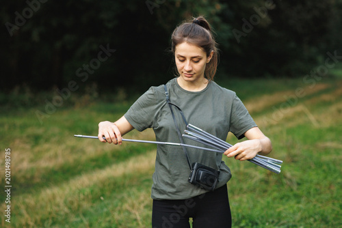 A young female tourist set up a tent in the forest