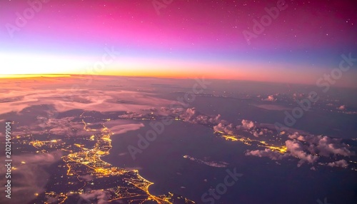 Aerial view of a city at dusk under a vibrant pink, orange, and blue sky