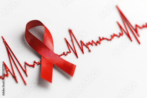 Red awareness ribbon placed on a white background with a heartbeat line design, symbolizing health awareness and support for various health initiatives