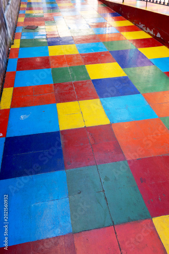 Vibrant checkered pathway displays bold red, blue, yellow, green squares. 