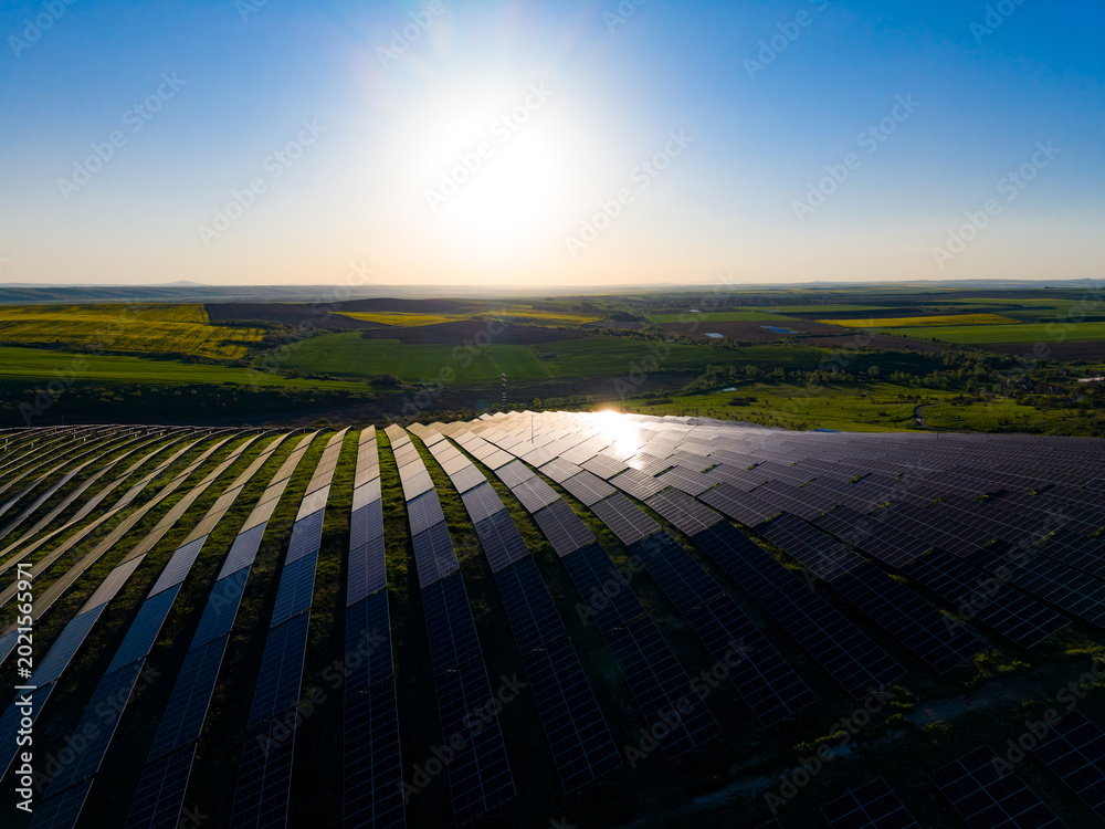 Fototapeta premium Solar panels cover a large field in a rural area during sunset in Spain, capturing sunlight for clean energy production in the early evening