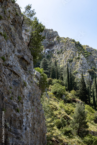 Vertical photo of a small church built on the rock in the mountains at Livadia city-Greece.