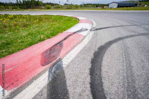 Tablou pe pânză Sharp turn on a professional asphalt race track with red and white striped rumbl