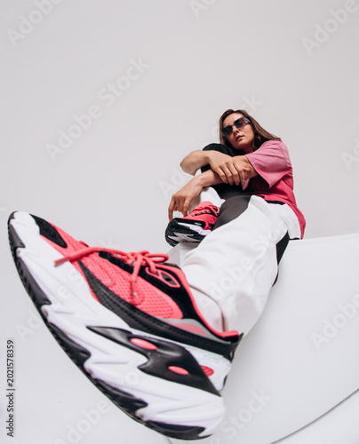 Emotional female hip hop dancer posing and dancing on a gray studio background. Dynamic wide-angle shot with joy, laughter, and urban street style
