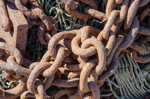 Close‑up of heavy rusted metal chains intertwined with ropes, showing weathered maritime texture and detail.