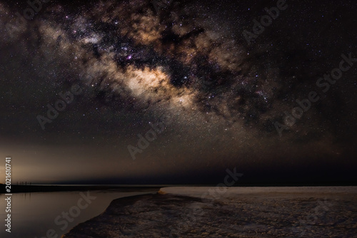Quadro em tela The Milky Way stretches above a quiet coastal inlet as soft reflections fade into the night
