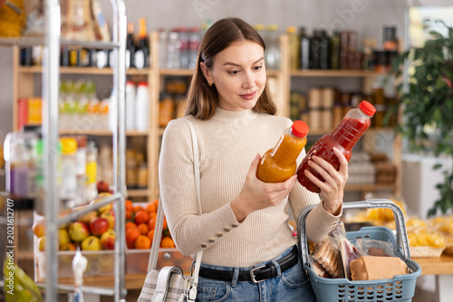 Obraz na plátně While shopping in grocery store, girl buyer choosing juice