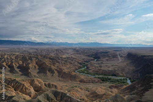 A winding river carves through rugged desert canyons under vast cloudy skies