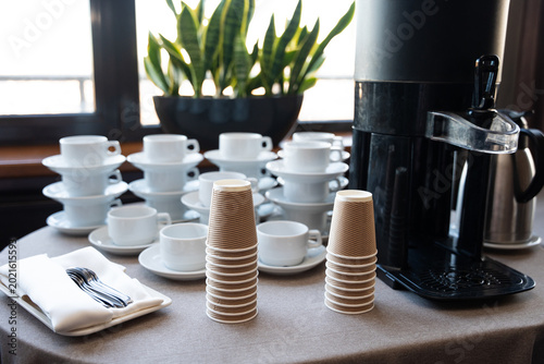 Self-service coffee station with stacks of cups and mugs