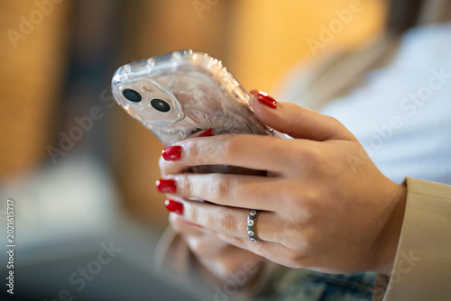 Woman with red manicure using a smartphone in a clear case