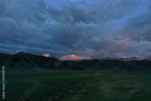 Dramatic twilight landscape with rolling hills and distant mountains under cloudy skies, Almaty, Kazakhstan