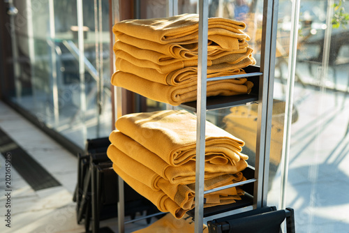 Schilderij op canvas Stacks of yellow blankets on a metal shelf on a terrace