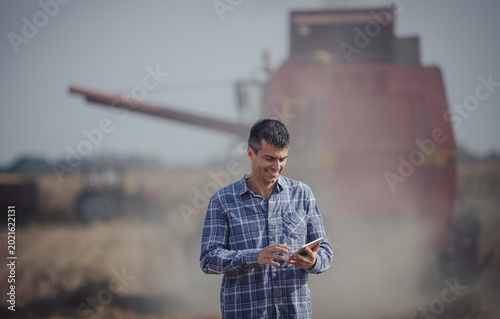 Schilderij op canvas Farmer standing in front of combine harvester