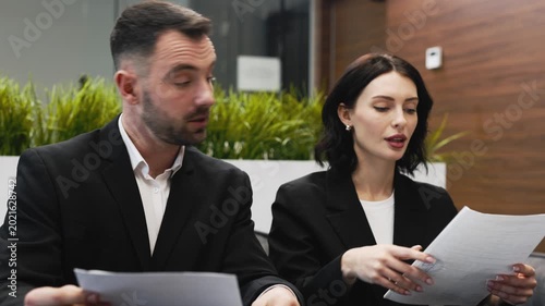 Young couple reviewing and signing real estate contract in modern office. Concept property purchase, rental agreement and legal consultation.
