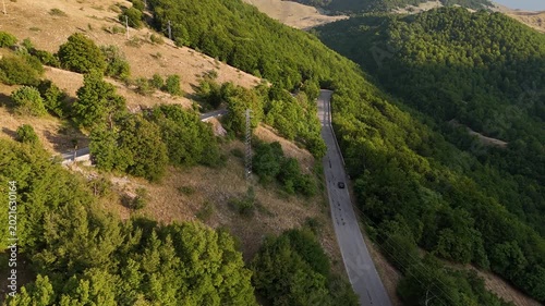 Winding road through lush green hills under a clear blue sky in the early afternoon creates a serene escape for travelers