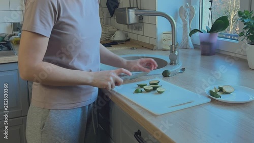 Feijoa fruit being sliced on cutting board. Preparation of fresh healthy food in home kitchen.