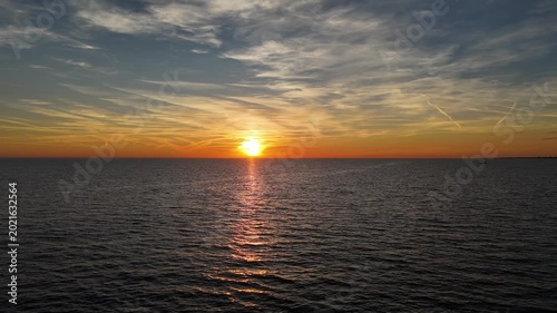 Golden sunset casts a warm glow over the calm ocean waves, creating a serene moment of beauty at dusk