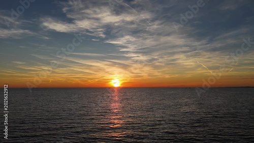Sunset paints the sky with golden hues over calm ocean waters near the horizon in a serene evening scene