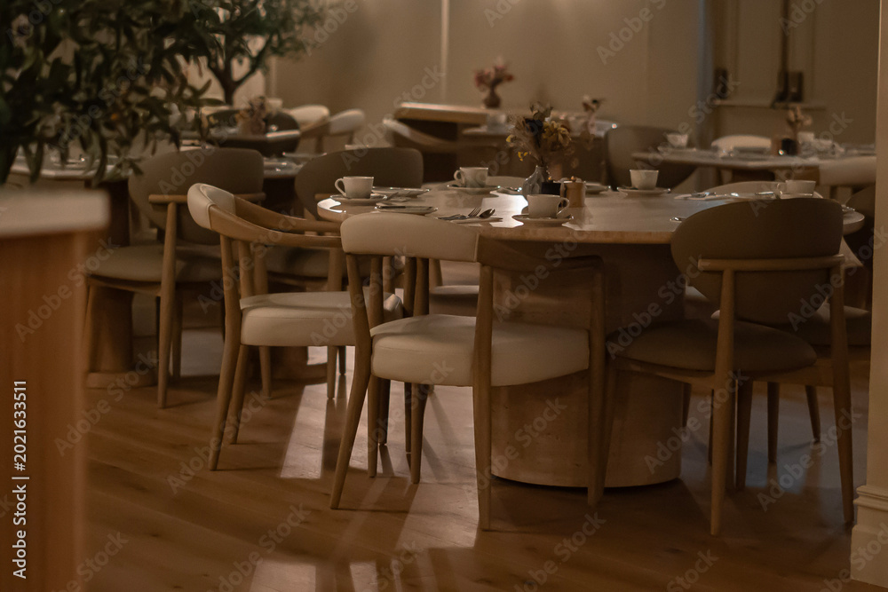 Fototapeta premium Cozy Modern Cafe Interior with Wooden Chairs and Warm Ambient Lighting
