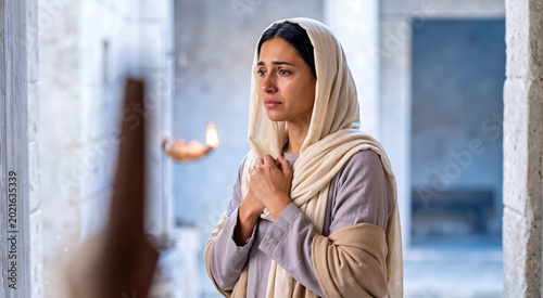 Weeping woman in cream veil and lavender robe praying with clasped hands. Hannah in a stone archway biblical scene
