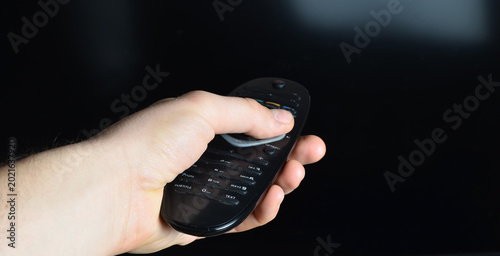 remote control in hand. male hand with a tv remote control turns on the tv.