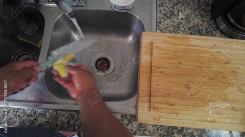 Person washing a kitchen knife in the sink after cooking