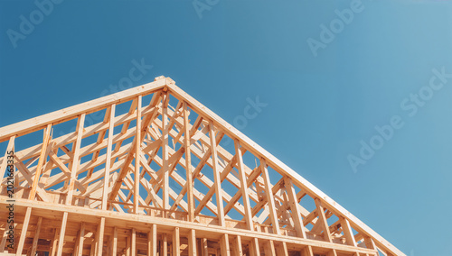 Obraz na płótnie 青空の下で木造住宅の骨組みが組み上がる建築現場写真