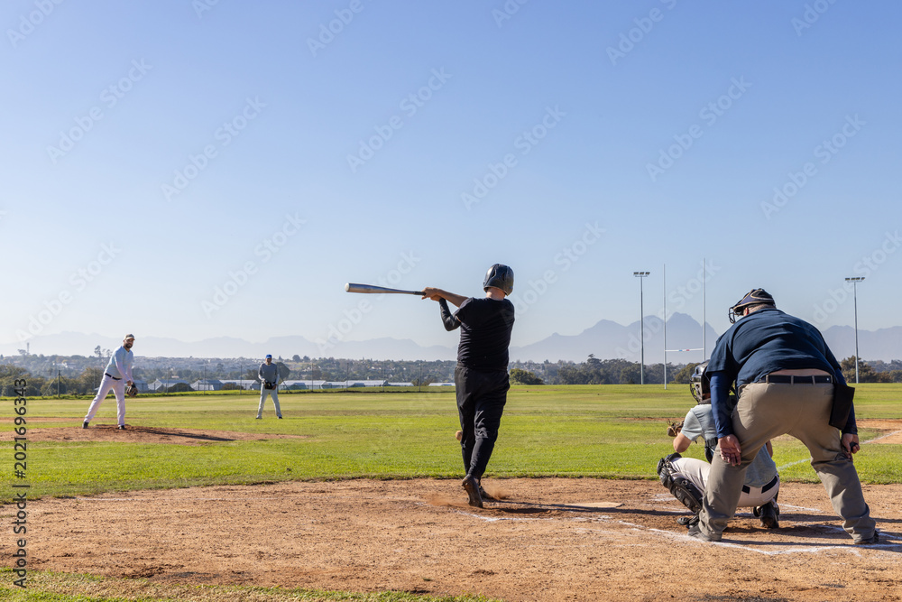 Obraz premium Mature male players, senior catcher in gear watching batter in black helmet swinging bat in box