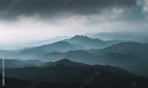 Misty mountains with fading layers under cloudy sky