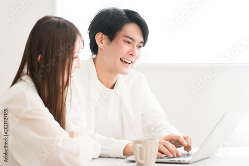 Bilde på lerret A young Asian couple or married couple sitting at the dining table, talking and discussing things while looking at their laptops
