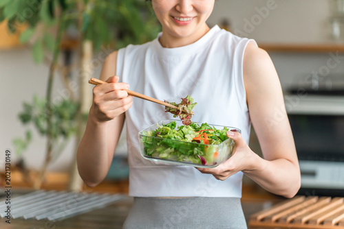 A young woman in sportswear eating a diet menu.