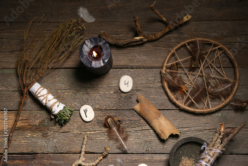 Fotografía Shaman's accessories with runes and burning candle on wooden background