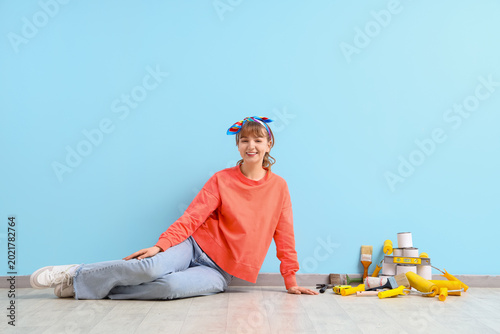 Photography Young woman with repair tools sitting near blue wall