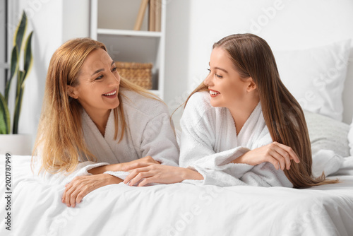 Young woman with her mother after shower lying in bedroom
