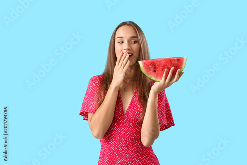 Young woman with fresh watermelon on blue background