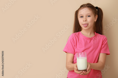 Photos Funny little girl with glass of milk on beige background