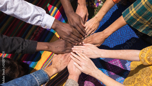 Bild auf Leinwand Diverse group of people from different ethnic backgrounds putting their hands to