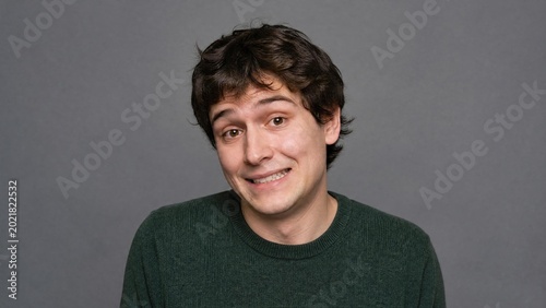 Portrait of Hesitant Young Man with Awkward Smile and Nervous Expression