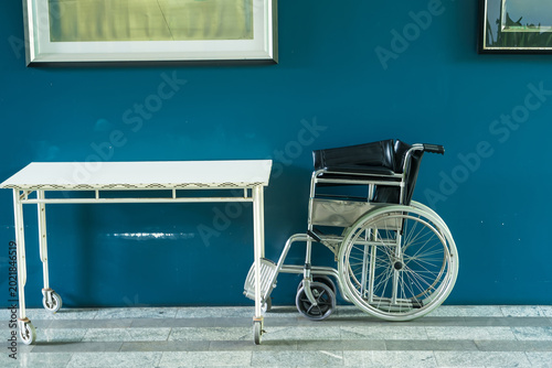 Accessibility and Inclusivity: A wheelchair, symbolic of mobility and assistance, is placed next to an empty table. The image represents support.