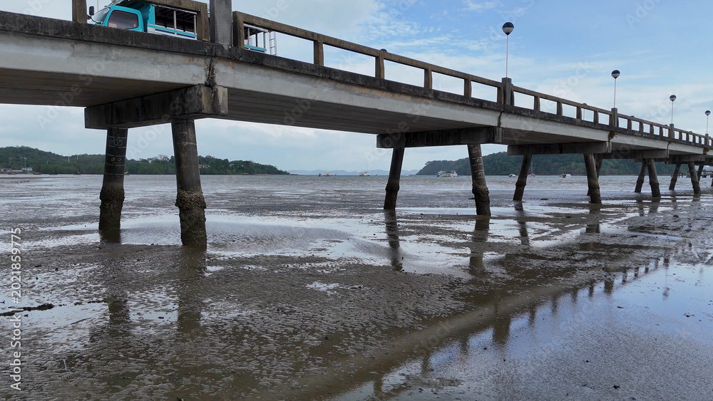Fototapeta premium Low Angle View of a Concrete Pier Over Muddy Coastal Flats